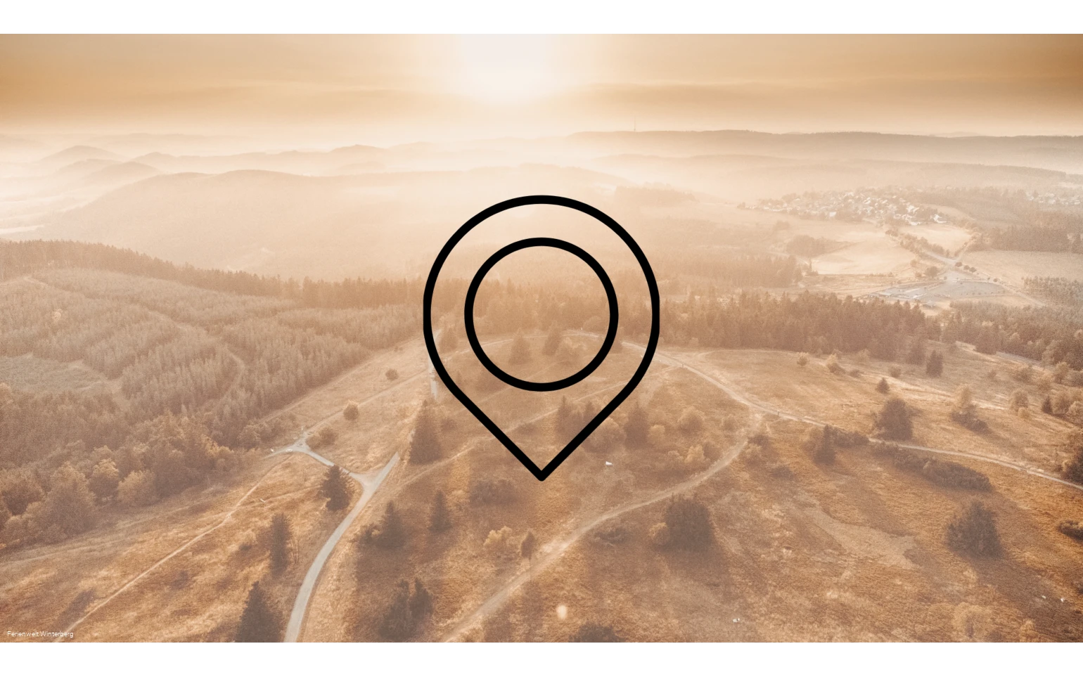 Drohnenaufnahme einer weitläufigen Landschaft aus Bergen, Wäldern und Wiesen mit der Zeichnung eines Markierungszeichens im Vordergrund. Dieses Bild dient als Symbolbild für Sehenswürdigkeiten.