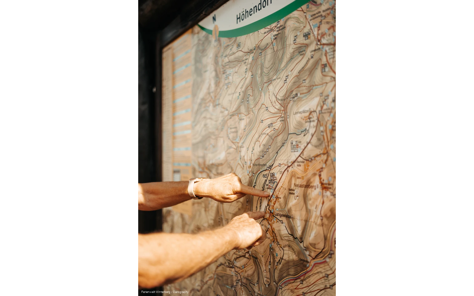 Zwei Hände, die mit dem Zeigefinger auf einer Wanderkarte auf etwas zeigen.
