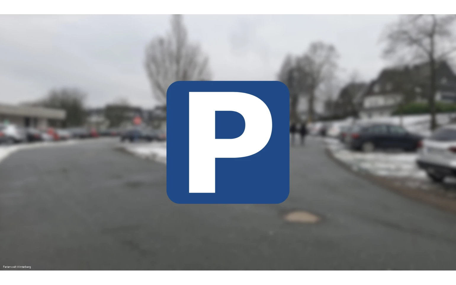Ein verschwommenes Bild eines Parkplatzes mit einem Parkplatzschild mit weißem P auf blauem Grund im Vordergrund. Dieses Bild dient als Symbolbild für Parkplätze.