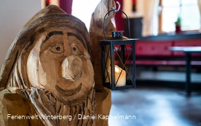 Ein aus Holz geschnitzter Zwerg mit einer Laterne in der Hand.