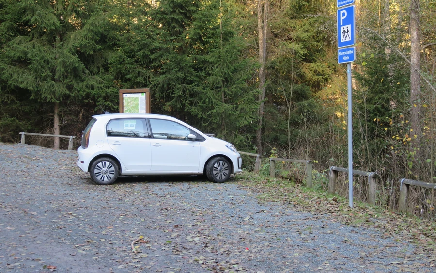 Kleines weißes Auto parkt auf Parkplatz im Wald. Kleines weißes Auto parkt auf Parkplatz im Wald.