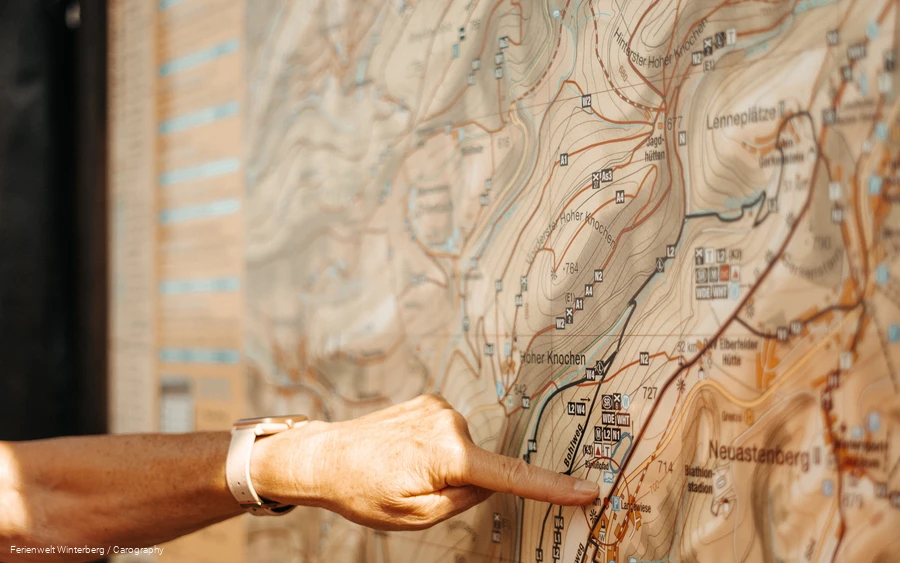 Zwei Hände, die mit dem Zeigefinger auf einer Wanderkarte auf etwas zeigen.