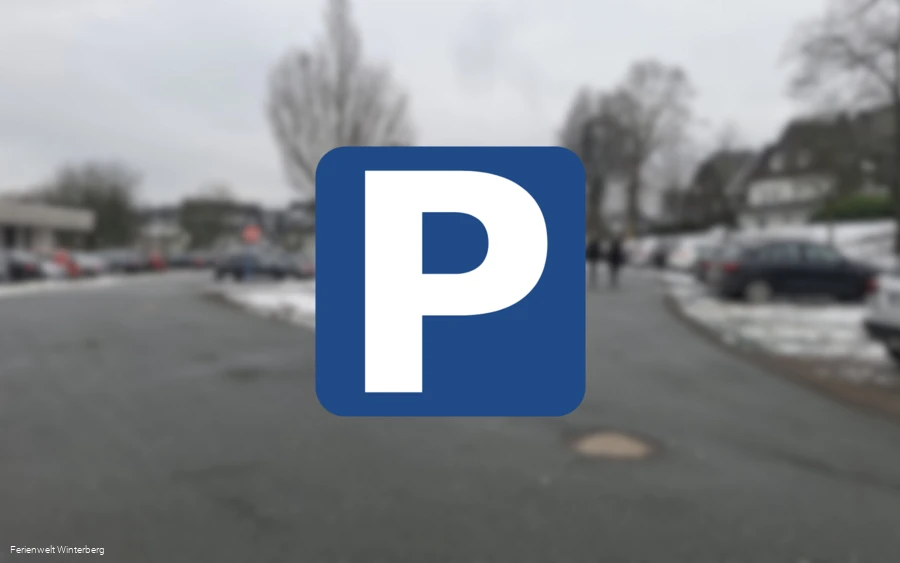 Ein verschwommenes Bild eines Parkplatzes mit einem Parkplatzschild mit weißem P auf blauem Grund im Vordergrund. Dieses Bild dient als Symbolbild für Parkplätze.