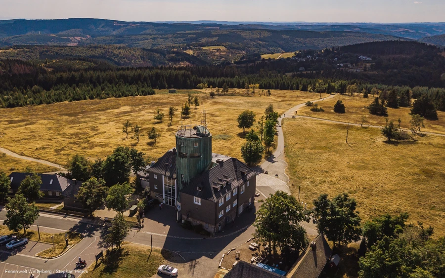 Drohnenaufnahme vom Astenturm mit der Wetterstation umgeben von weiter Heidelandschaft und Wäldern.