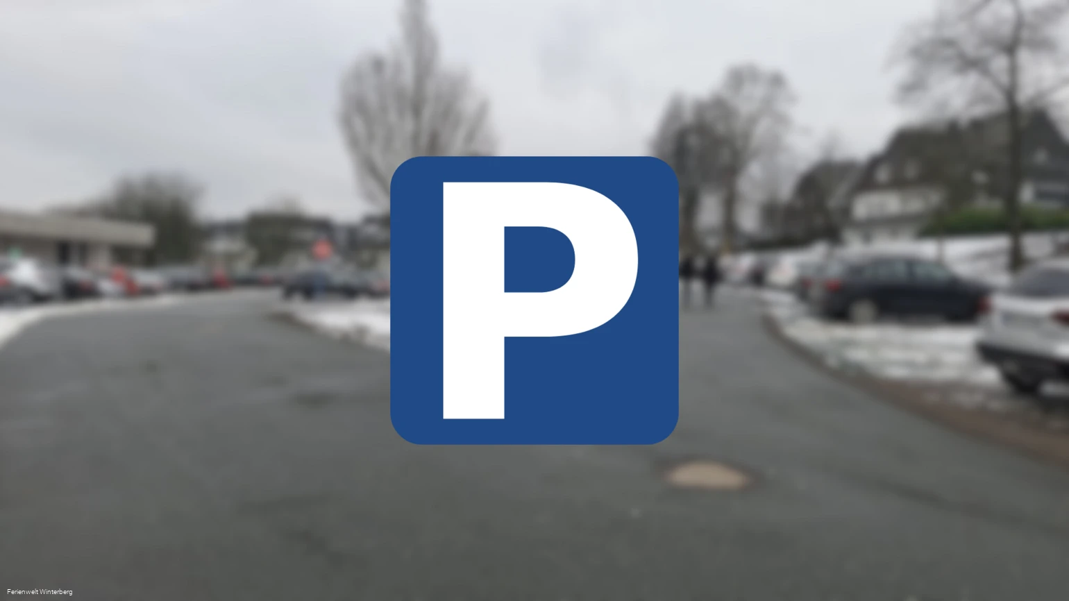 Ein verschwommenes Bild eines Parkplatzes mit einem Parkplatzschild mit weißem P auf blauem Grund im Vordergrund. Dieses Bild dient als Symbolbild für Parkplätze.